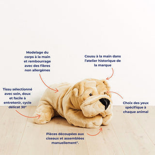 Ma peluche chien Hector de La Pelucherie. Un chien en peluche beige, cousu à la main dans l’atelier de la marque, avec des yeux choisis spécifiquement, un corps modelé et rembourré à la main avec des fibres non allergènes, un tissu doux lavable à 30°, et des pièces de fourrure découpées et assemblées manuellement.